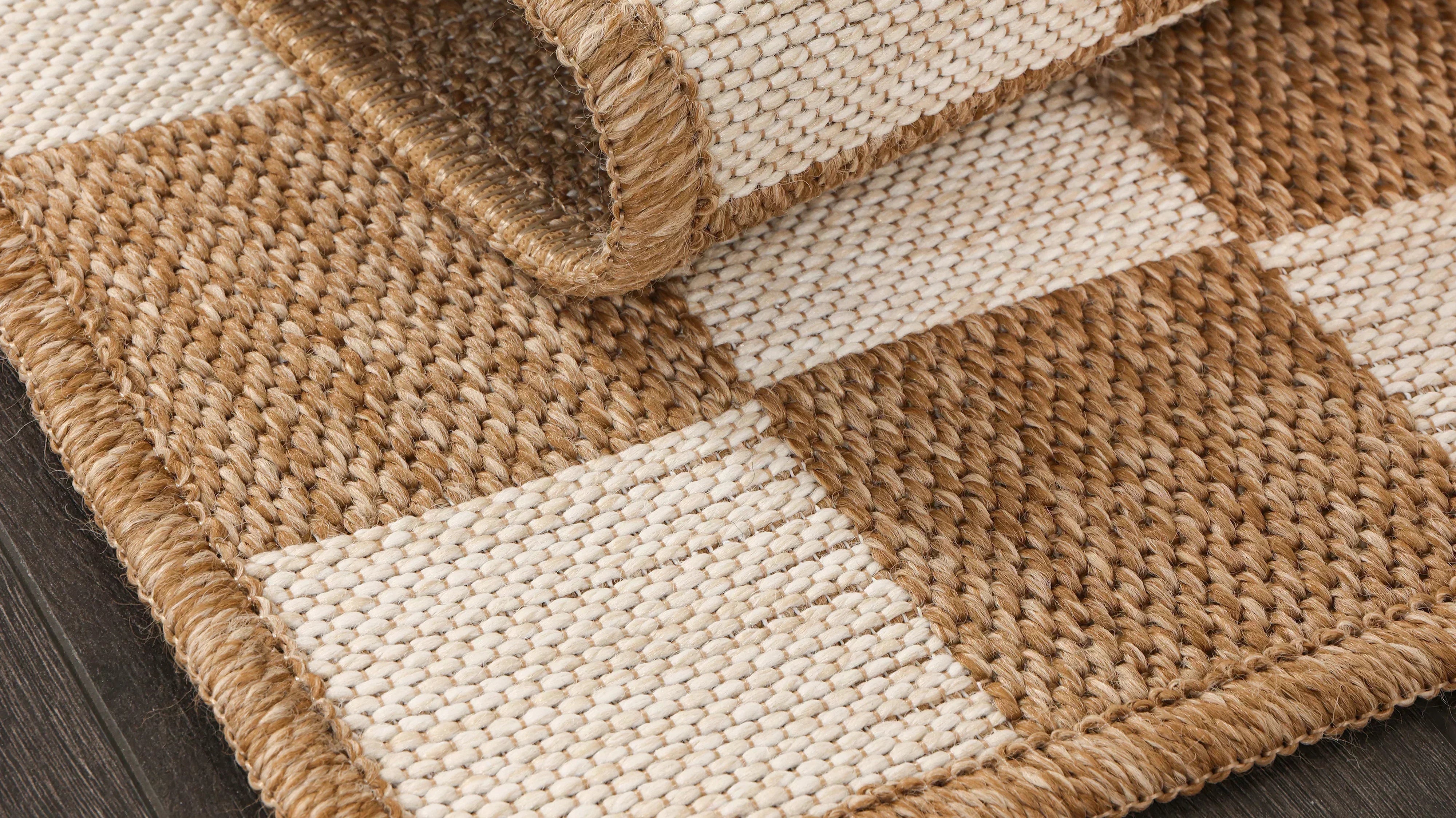 Close-up of a beige checkered textured area rug adding warmth and dimension to neutral home decor.