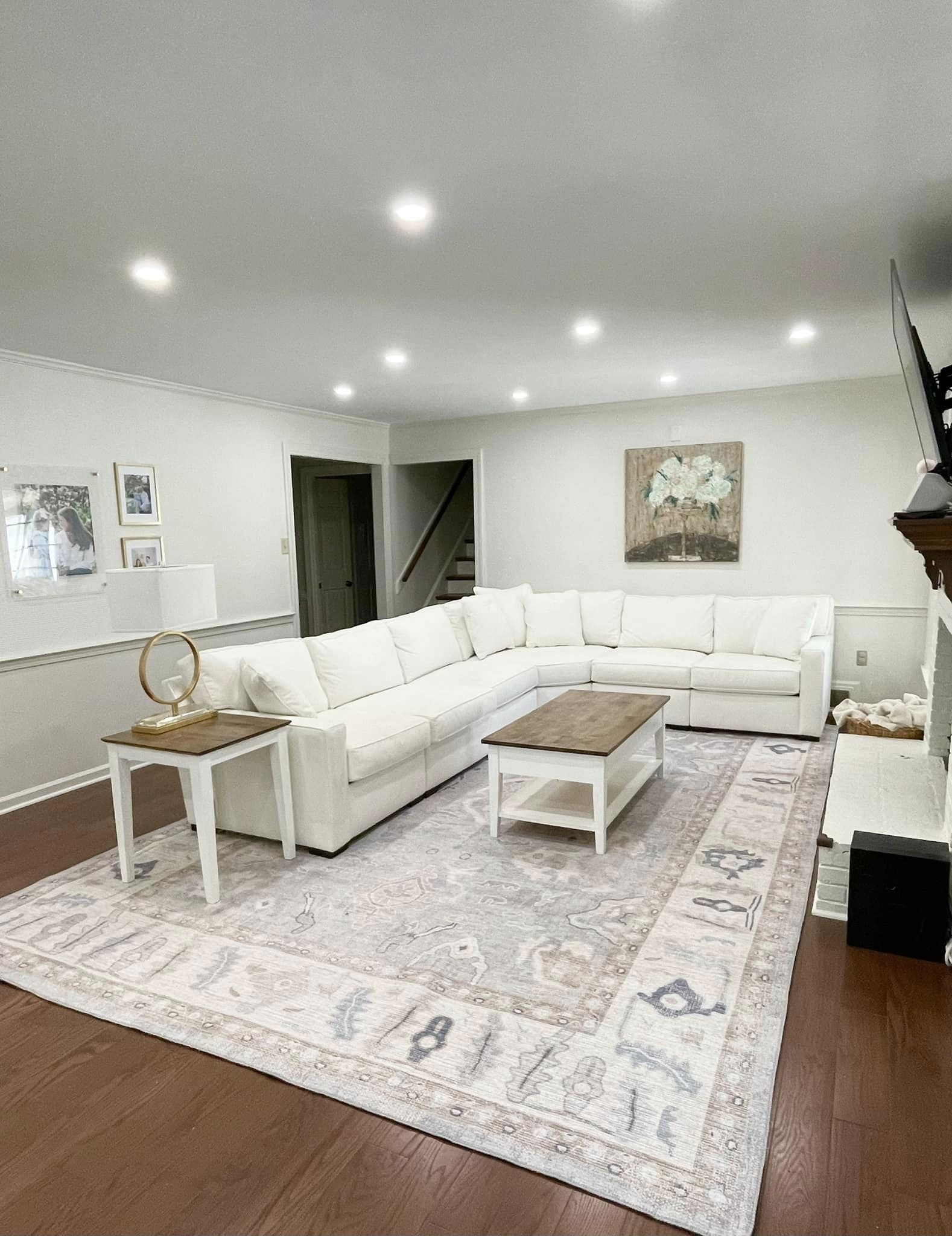 White minimalist living room styled with a gray Oushak floral rug adding subtle texture and warmth to a modern interior