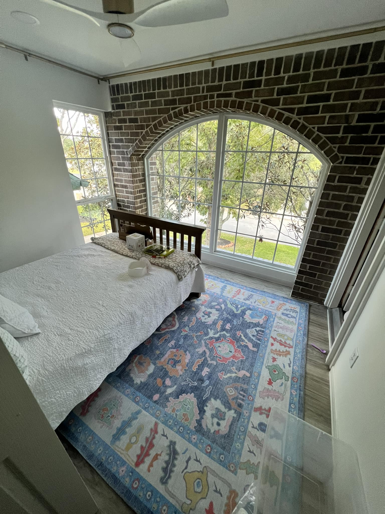 Large blue floral area rug placed under a bed in a bright bedroom