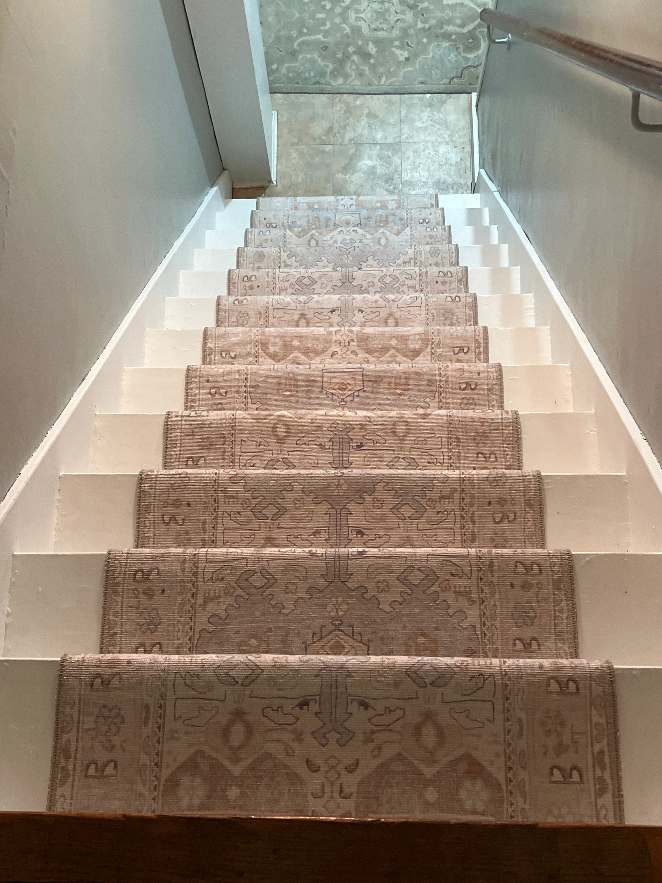 Elegant staircase with a neutral-tone runner rug, showing a soft textured surface that adds both safety and style to stairs in a modern home interior.