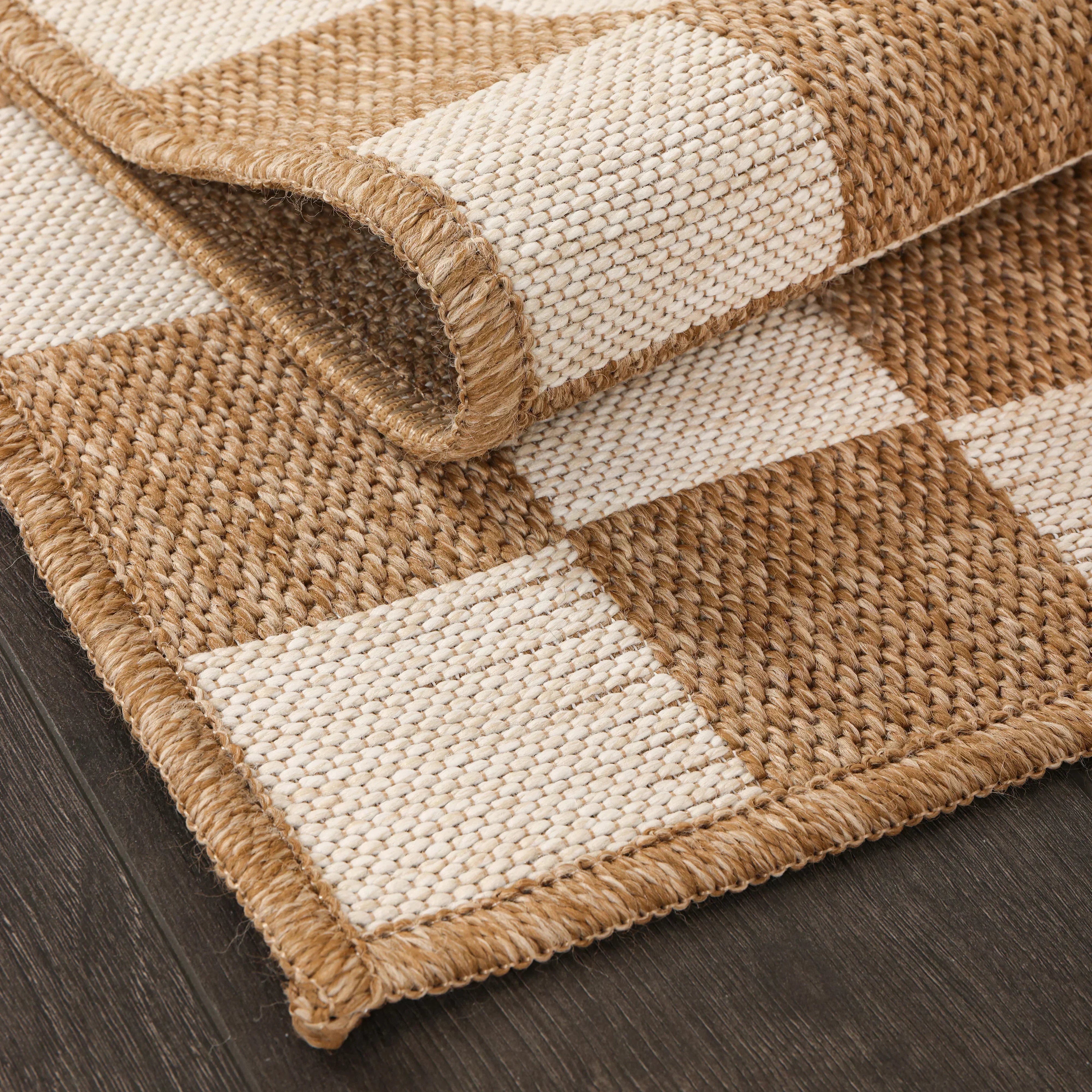 Close-up of a beige checkered textured area rug adding warmth and dimension to neutral home decor.