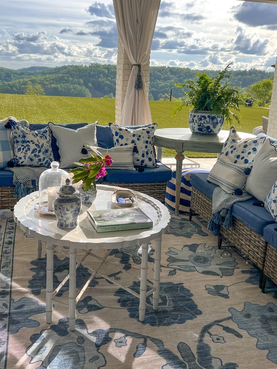 Cozy outdoor balcony seating area featuring a blue and white floral rug that adds charm and color to the small space.