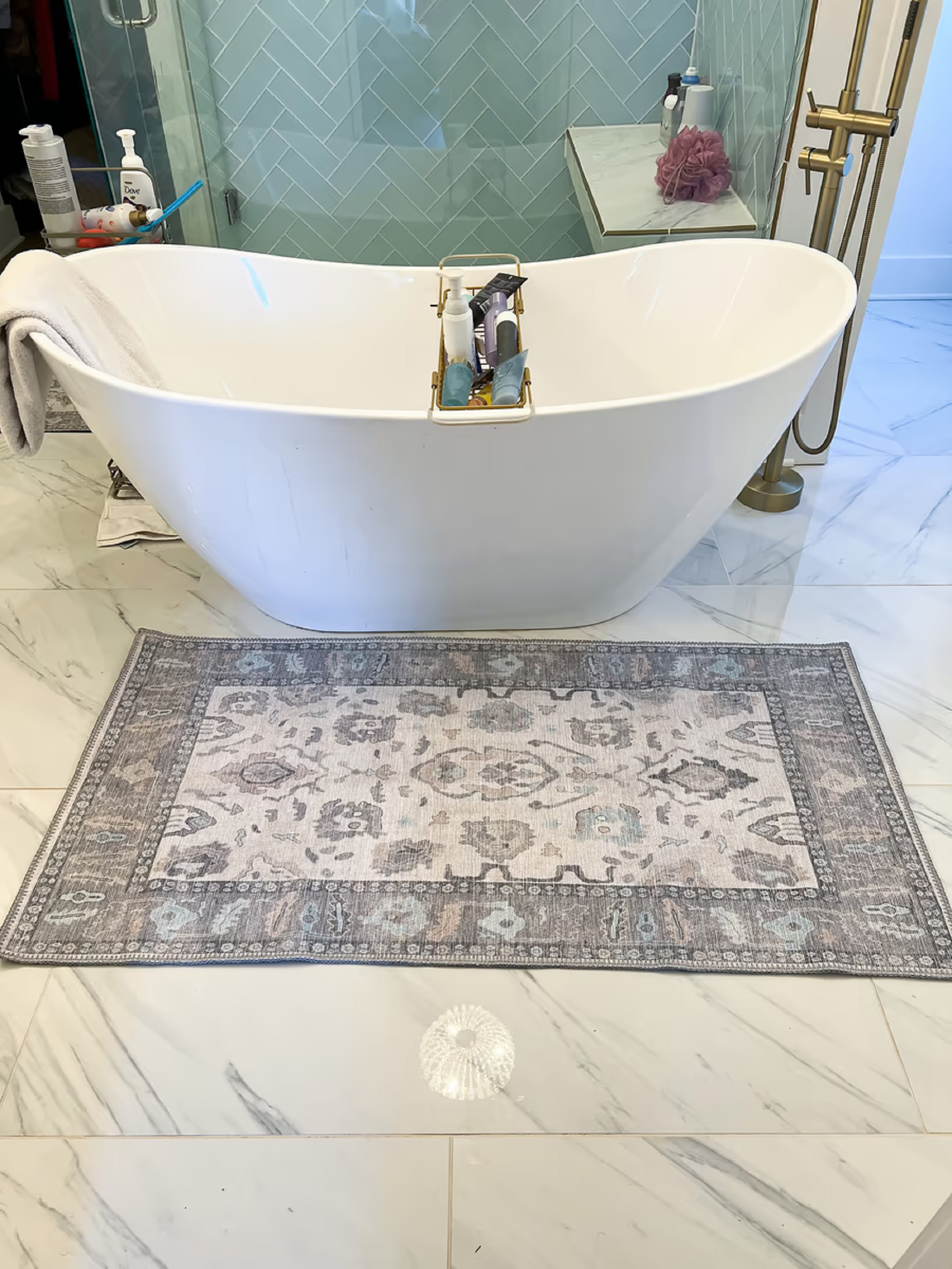 Minimalist bathroom with a sleek gray rug placed beside the bathtub, adding a clean and modern touch to the neutral-toned space.