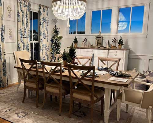 Dining room with a wooden table and chairs, decorated for Christmas, under a chandelier.  Dining Room Rugs - Fame Rugs.