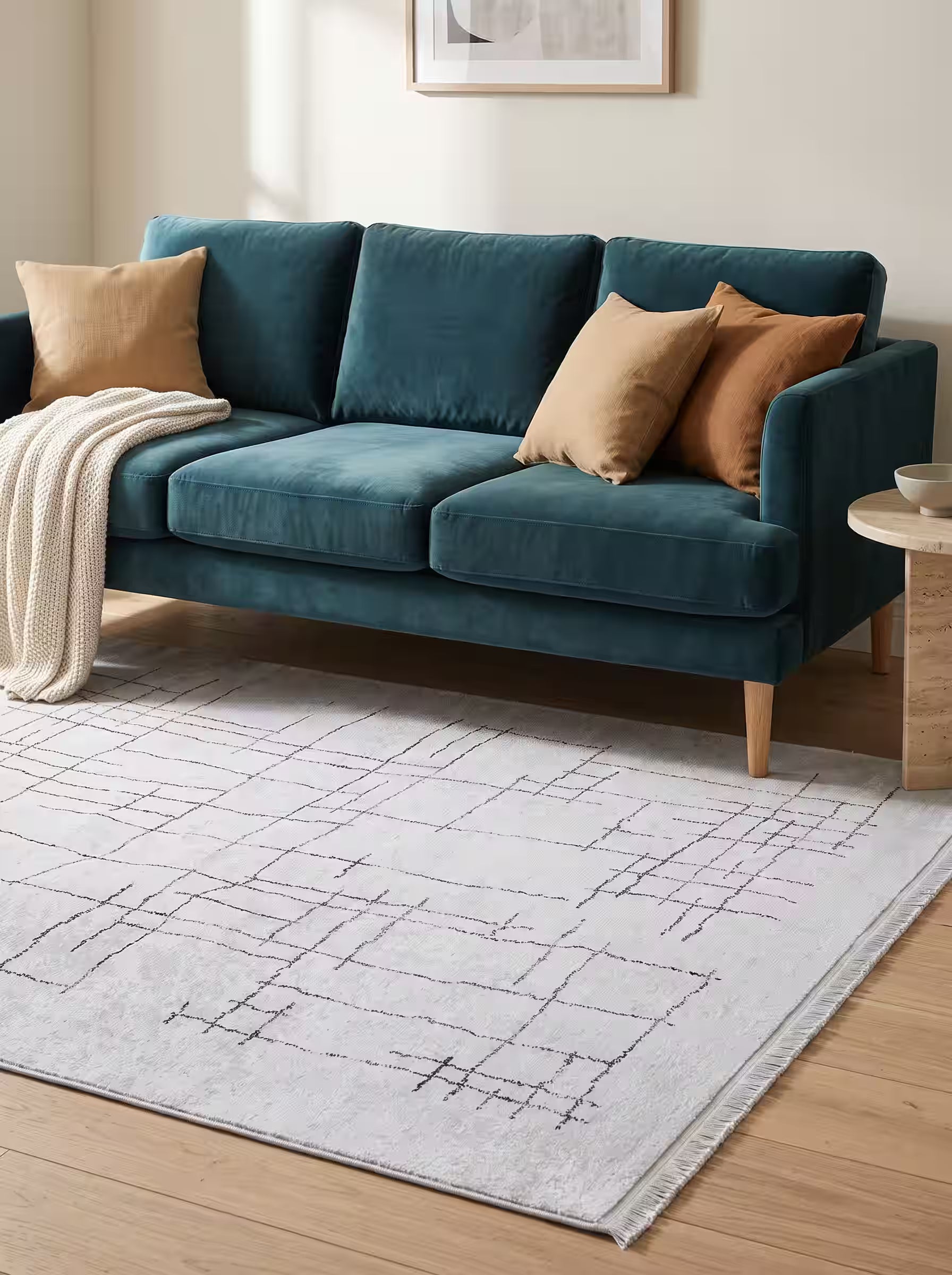 Cream and oatmeal area rug paired with a deep teal velvet sofa in a modern living room