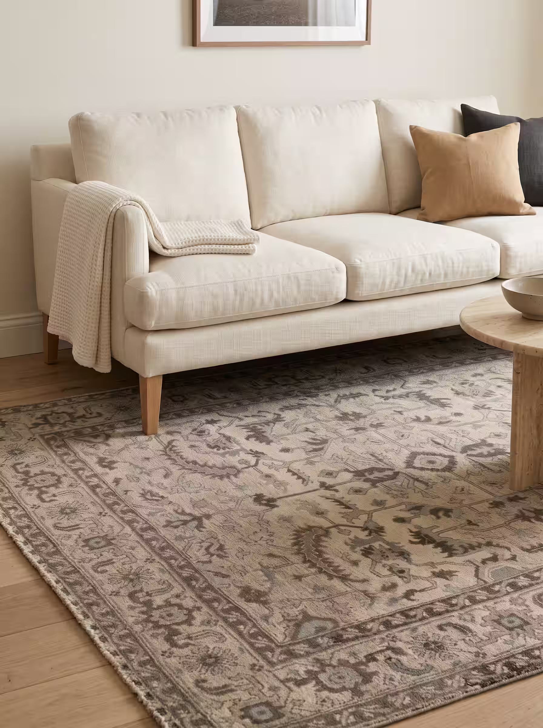 Taupe and camel area rug paired with a cream white linen sofa in a modern living room
