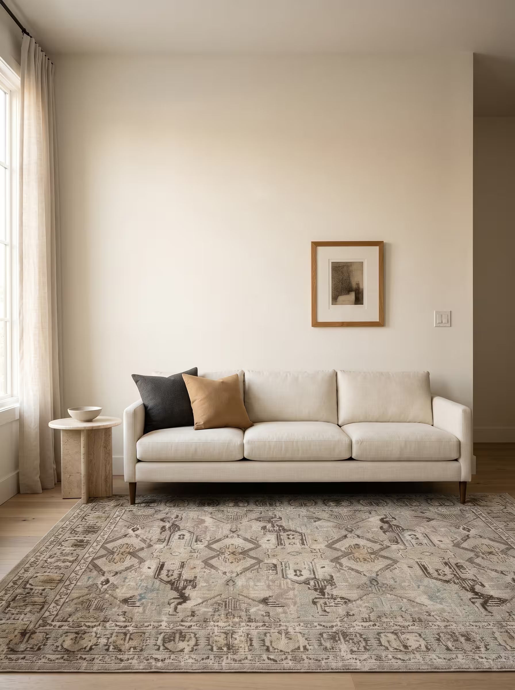 Taupe and camel area rug in a living room with warm off-white painted walls